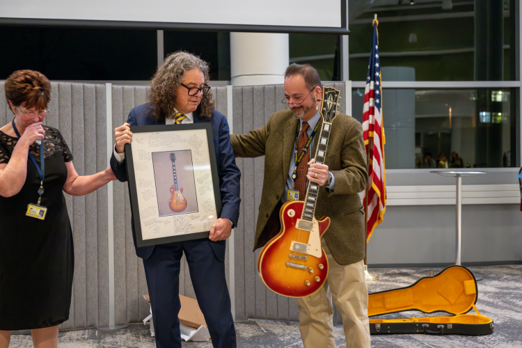 Jeff Myers with Beth Minors Van Loton and Ul Balis receiving picture and Les Paul guitar.